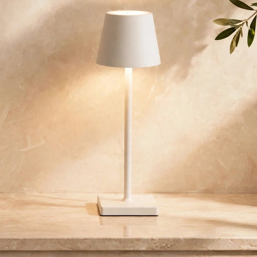 Lámpara LED portátil sin cables en color blanco, encendida sobre una repisa de mármol